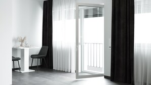 A modern room with a white table, two chairs, a balcony with a glass door, and sheer curtains. - The Residences - Apartments Frankfurt (Offenbach am Main)