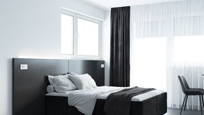 A modern bedroom with a bed, a chair, and a window. - The Residences - Apartments Frankfurt (Offenbach am Main)