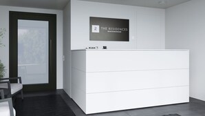A modern, minimalist reception desk with a framed sign above it. - The Residences - Apartments Frankfurt (Offenbach am Main)