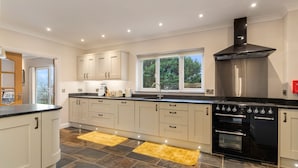 A modern kitchen with white cabinets, a black stove, and a window overlooking greenery.