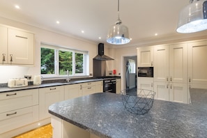 A modern kitchen with white cabinets, a granite countertop, and a black range hood.