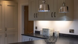 A kitchen with white cabinets, a black countertop, and two pendant lights.