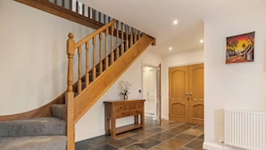 A staircase with wooden railings, a console table with drawers, and a painting on the wall.
