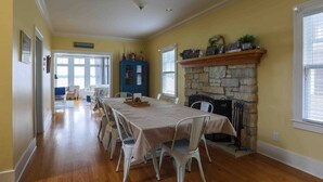 A dining room with a long table, white chairs, and a stone fireplace. - Beautiful 3600sqft Cottage on Lake Maxinkuckee in Culver Indiana. (Culver)