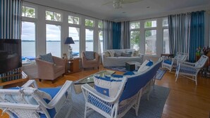A spacious living room with large windows, a ceiling fan, and a view of the water. - Beautiful 3600sqft Cottage on Lake Maxinkuckee in Culver Indiana. (Culver)
