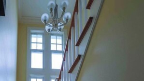 A staircase with wooden steps and a white handrail, leading to a door with a window. - Beautiful 3600sqft Cottage on Lake Maxinkuckee in Culver Indiana. (Culver)