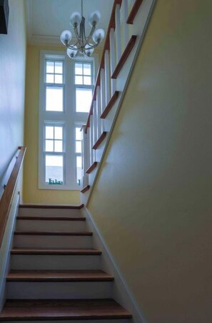 A staircase with wooden steps and a white handrail, leading to a door with a window.