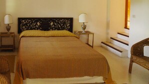 A hotel room with a large bed, two bedside lamps, a chair, and a staircase.