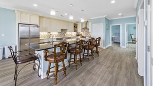 A spacious kitchen with a central island, bar stools, and stainless steel appliances.