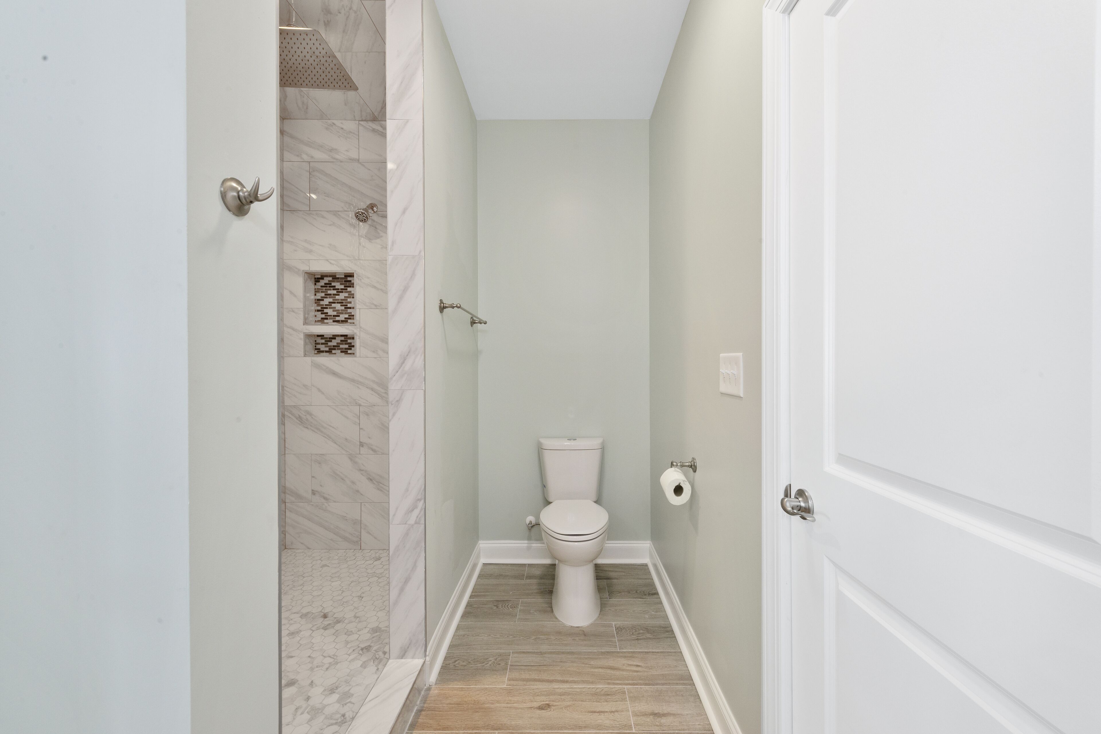 A bathroom with a toilet, shower, and tiled floor.