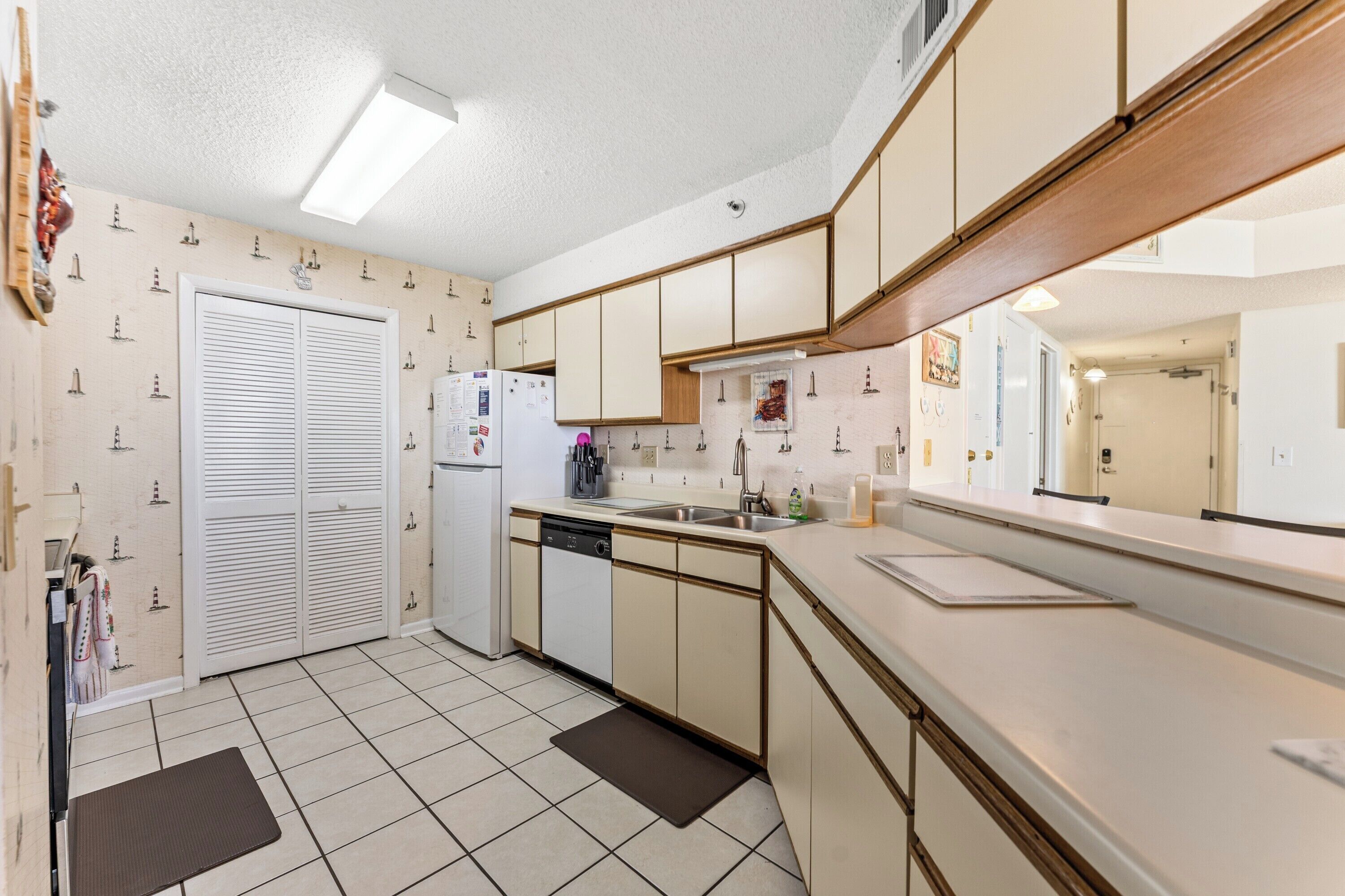 A compact kitchen with a dishwasher, a refrigerator, and a sink.