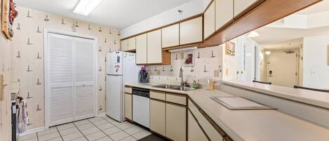 A compact kitchen with a dishwasher, a refrigerator, and a sink.