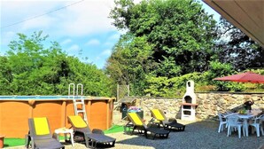 Un espace extérieur avec une piscine, des chaises longues, un petit bassin et un mur en pierre.