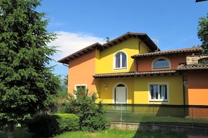 A two-story house with a yellow facade, a brown roof, and a small balcony. - Villa Private pool, mountain views (Toscana)