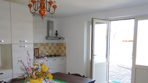 Une cuisine avec des meubles blancs, une table à manger agrémentée d’un centre de table jaune et un lustre.