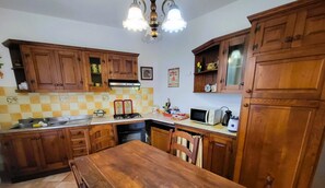 Una cuina amb armaris de fusta, forns, microones i una taula de dinar.