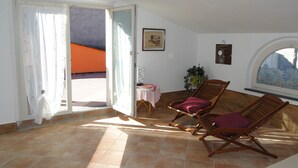 Une pièce baignée de lumière, avec deux chaises en bois, une table recouverte d’une nappe blanche et une plante en pot.