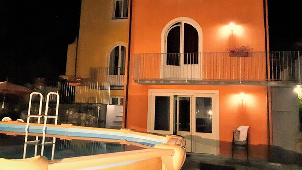 Un bâtiment à deux étages doté d’une piscine, d’un balcon avec une balustrade et d’une porte à panneaux de verre.