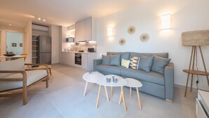 A modern living room with a grey sofa, a white coffee table, and a wooden floor. - Lovely 2 Bedroom Apartment Vouliagmeni (Vari-Voula-Vouliagmeni)