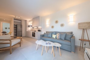 A modern living room with a grey sofa, a white coffee table, and a wooden floor.