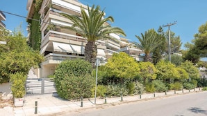 A multi-story residential building with balconies, surrounded by greenery and a clear sky. - Lovely 2 Bedroom Apartment Vouliagmeni (Vari-Voula-Vouliagmeni)