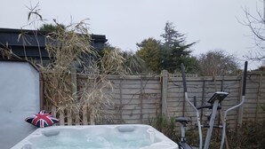 Una vasca idromassaggio in legno, attrezzature per esercizi e un cuscino a forma di bandiera in un ambiente esterno.