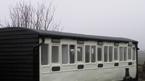 Un vagone ferroviario fermo con diverse finestre, un tetto nero e una carrozzeria bianca.