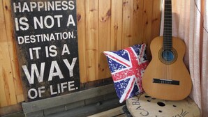 Una chitarra, un cuscino con la Union Jack e un cartello motivazionale su un muro di legno.