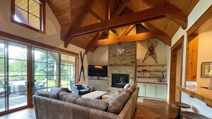 A spacious living room with a large sectional sofa, a fireplace, and a stone wall. - Crosswater Luxury Retreat with Access to Exclusive Golf (Sunriver)