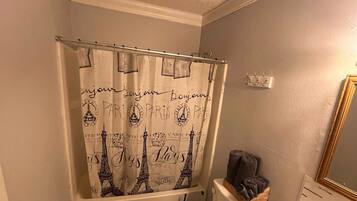 Un baño con inodoro, lavamanos y cortina de ducha con diseños parisinos.