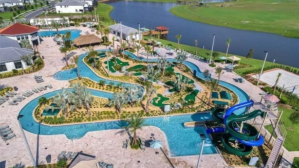 Luchtbeeld van een resort met een kronkelend zwembad, een glijbaan en een meer.
