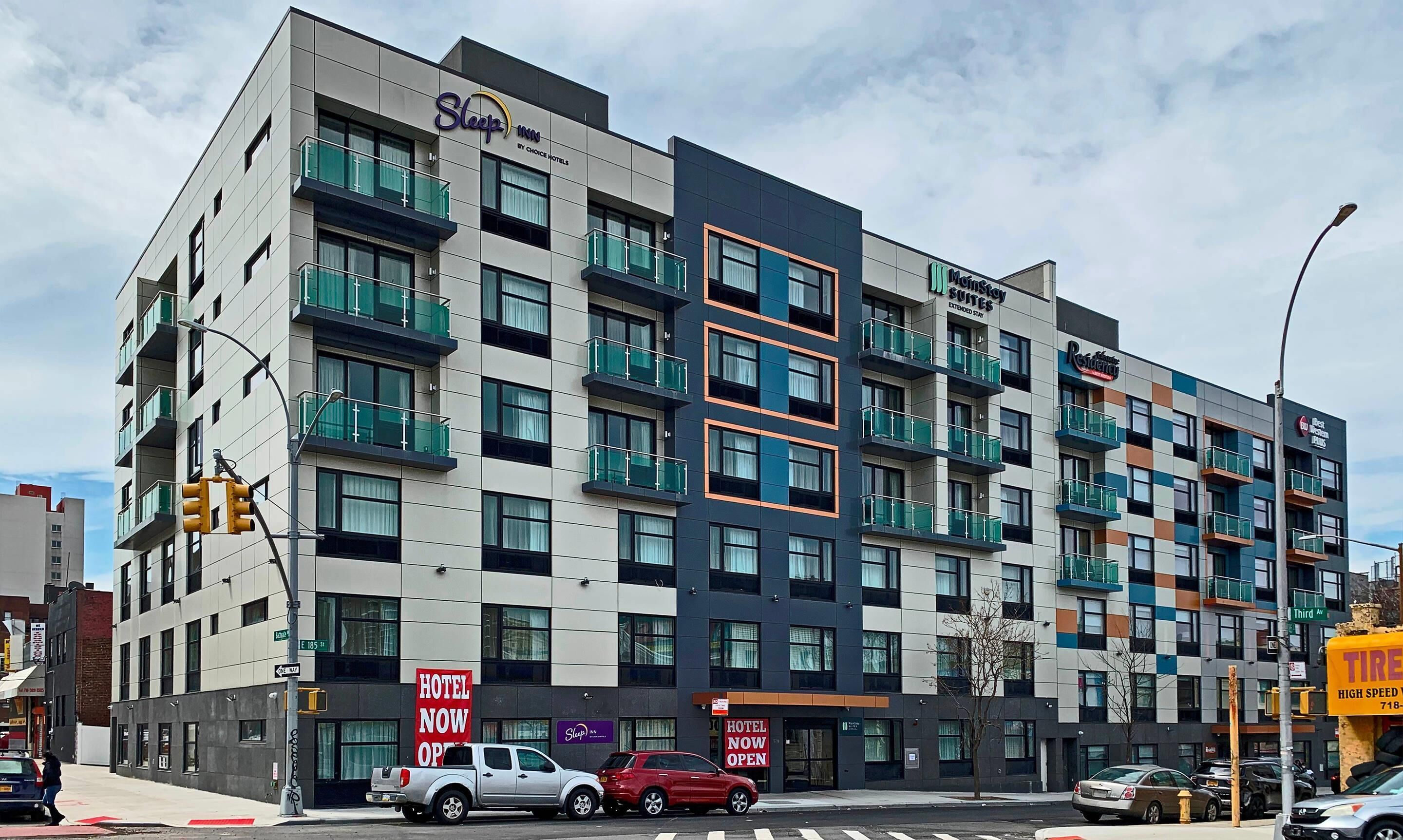 A multi-story hotel with balconies, signage indicating availability, and a street view with vehicles.
