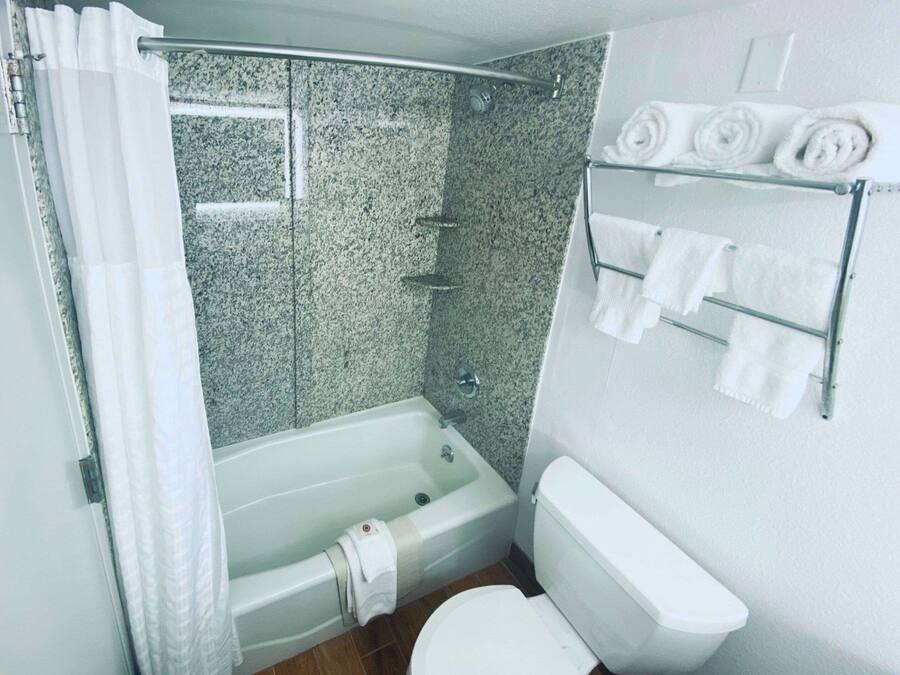 A bathroom with a bathtub, shower, and toilet. There are towels on a rack.
