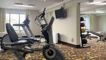 Un gimnasio de hotel con cintas de correr, una bicicleta estática y un banco para pesas.