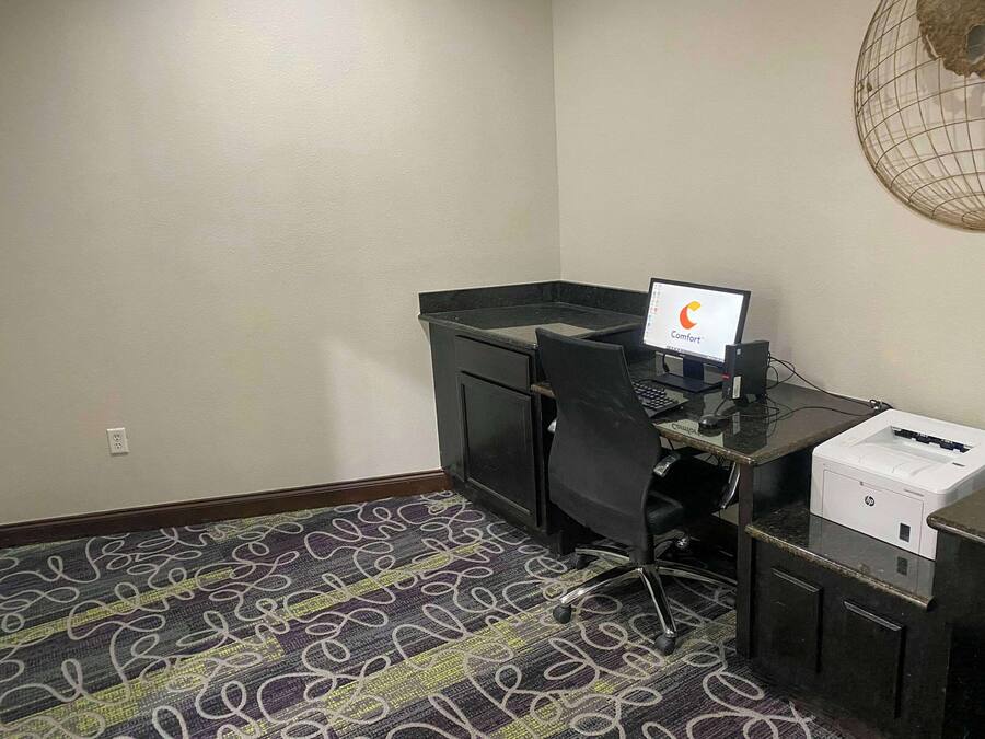 Habitación de hotel con escritorio, computadora, impresora y alfombra estampada.