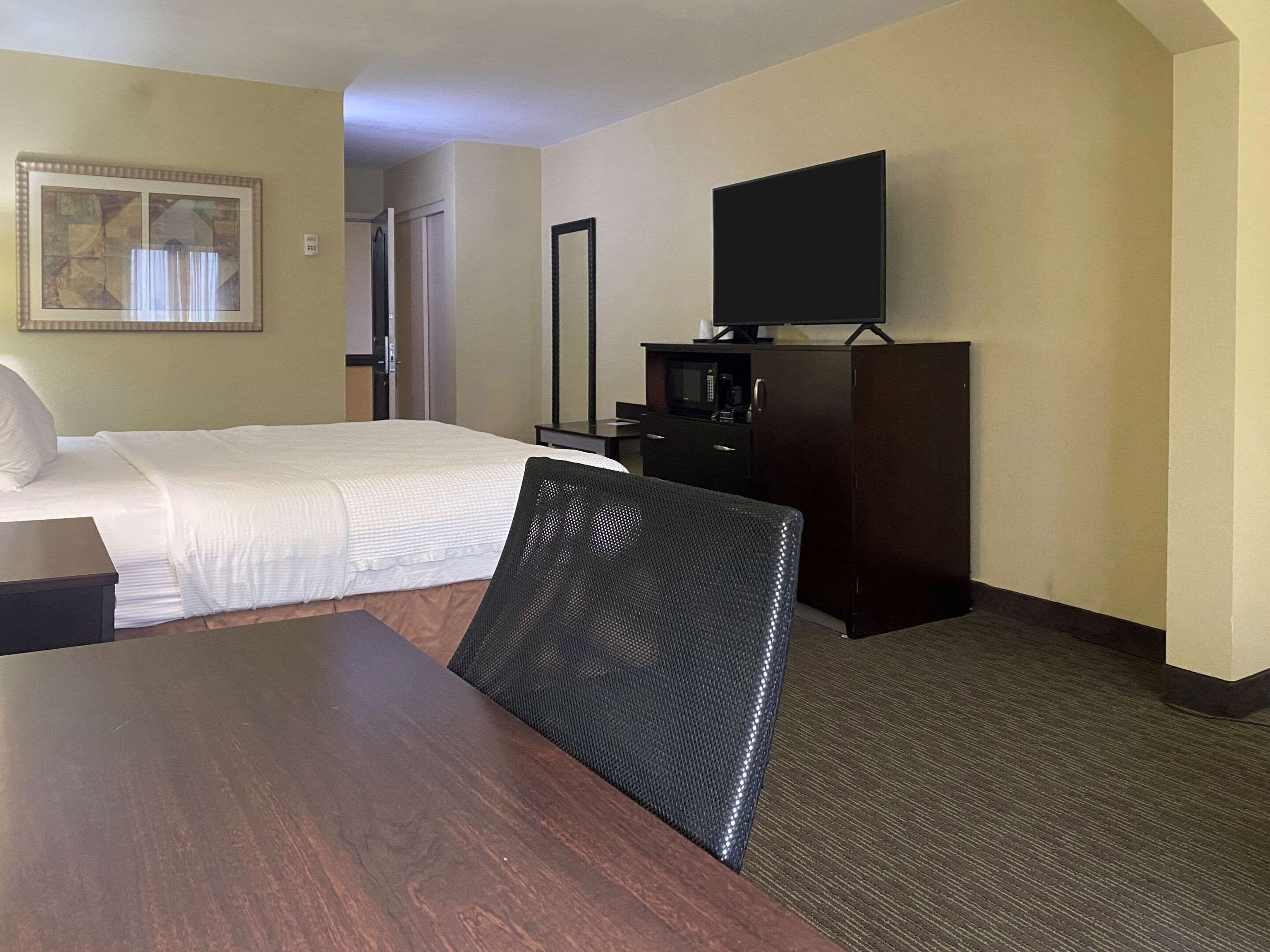 Una habitación de hotel con una cama, un televisor en un mueble, una silla y una mesa.