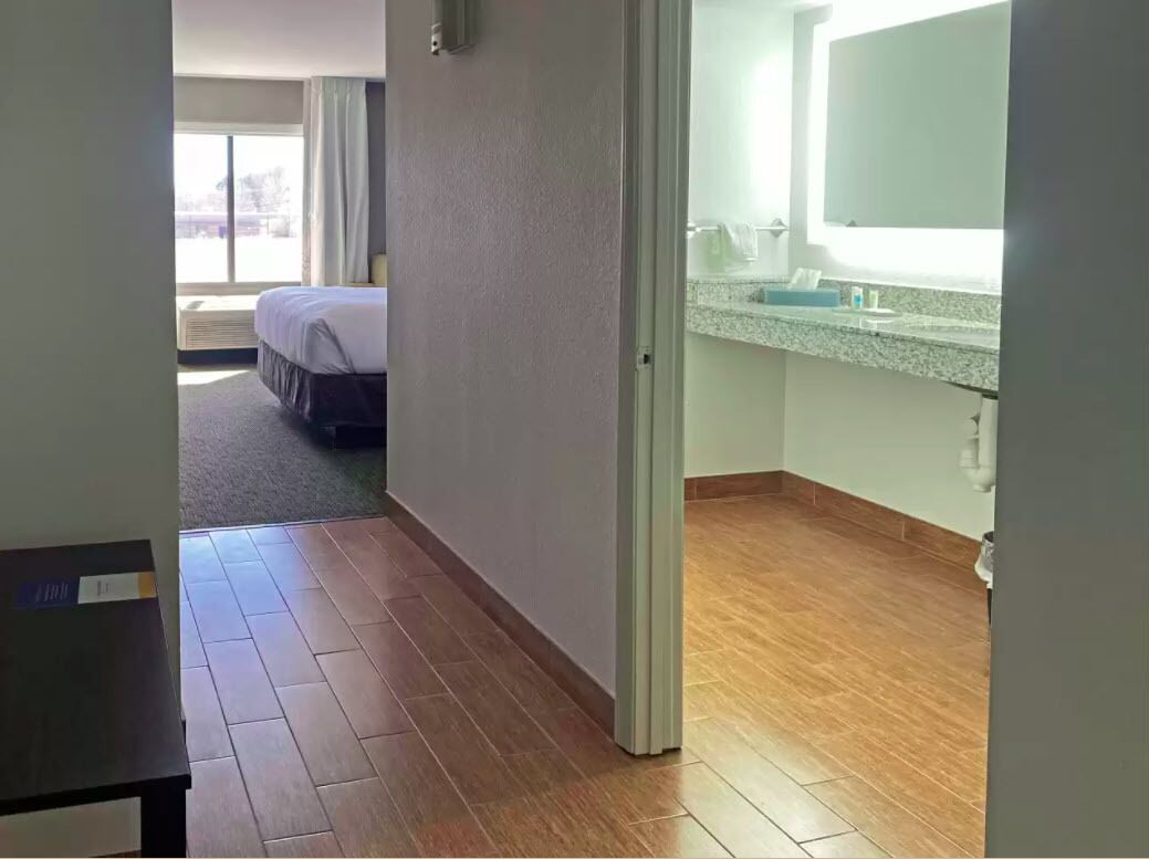 Une chambre d’hôtel avec un lit, une salle de bain équipée d’un lavabo et d’un miroir, et une vue sur l’extérieur.