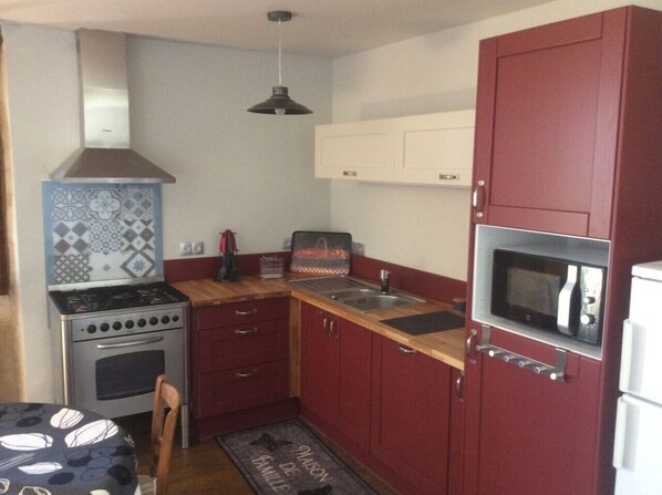 A compact kitchen with a stove, microwave, and sink.