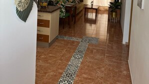 Un amplio espacio habitable con una mesa de comedor, sofá y una zona de cocina con piso de cerámica.