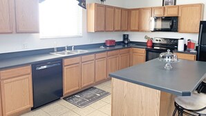 A modern kitchen with wooden cabinets, a dishwasher, a microwave, and a coffee maker. - Spacious pool home with games room and hot tub (heating included) (Davenport)