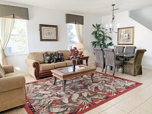 A living room with a sofa, coffee table, and dining area with chairs.