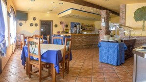 Un restaurante con mesas y sillas de madera, una zona de bar y un mural en la pared.