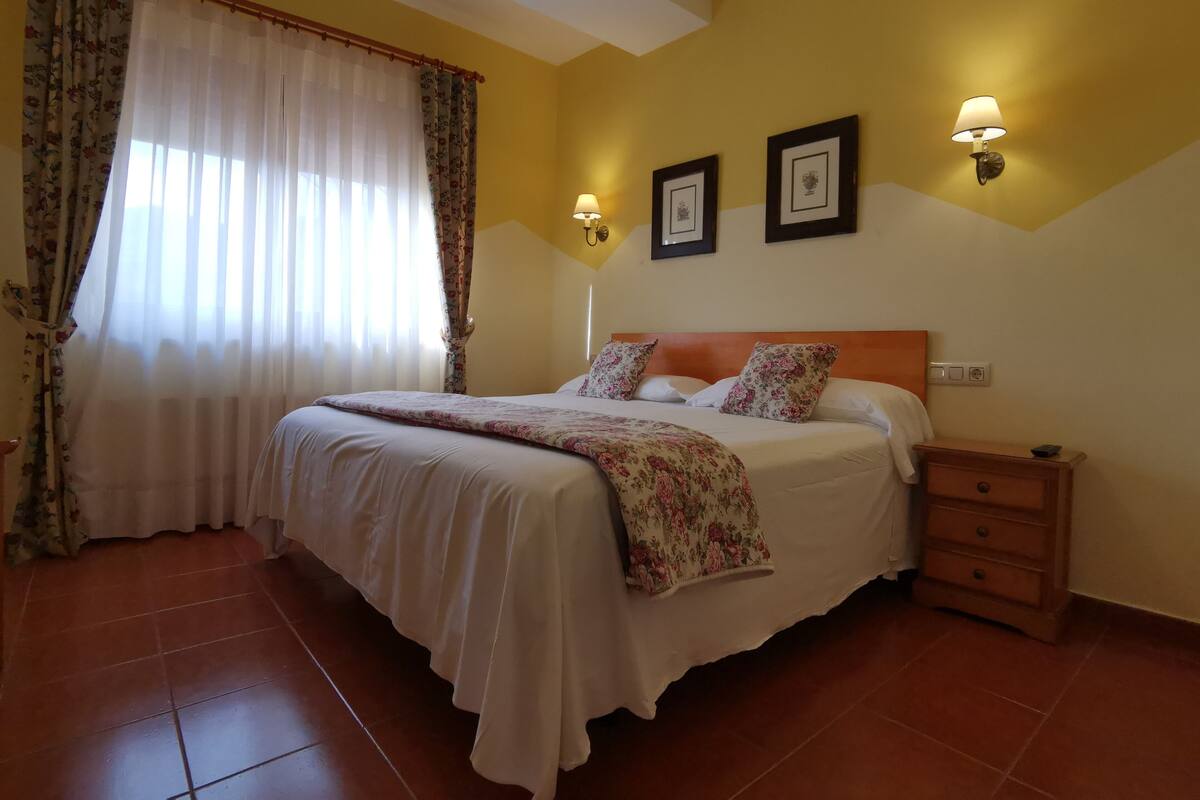 A bedroom with a bed, nightstand, and wall-mounted lamps.