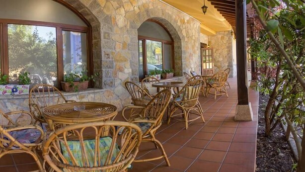 Un patio cubierto con paredes de piedra, mobiliario de mimbre y plantas en macetas.