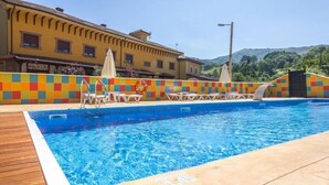 Una piscina con cubierta de madera, paredes de azulejos coloridos y sillones de descanso.