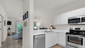 A modern kitchen with white cabinets, stainless steel appliances, and a built-in dishwasher. - 🐟1st Floor with Bikes-Coach's Sand Dollar (Santa Rosa Beach)