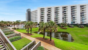 A modern hotel with multiple floors, a central courtyard with a pond, and palm trees. - ⭐Walk 2 Beach-Gulf + Pool Views-2 Pools + Hot Tub-2BR Mainsail 213⭐ (Miramar Beach)