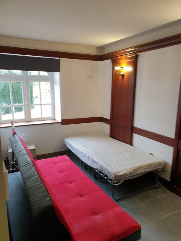 A small, compact room with a single bed, a bench, and a window. - Apartment building with a spa for 6 people near the ocean (Hôpital-Camfrout)