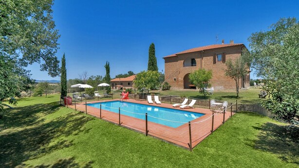 A rectangular swimming pool with a tiled deck, surrounded by a low brick wall and a grassy lawn. There are white lounge chairs and umbrellas along the poolside. - LA ROSA CANINA     . (Castiglione del Lago)