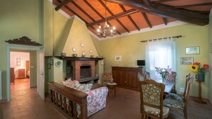 A cozy living room with a fireplace, wooden furniture, and a dining area. - LA ROSA CANINA     . (Castiglione del Lago)